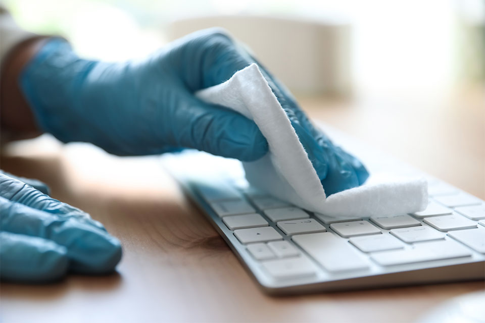 Woman sanitizes keyboard.