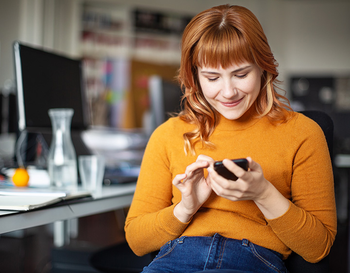 Young woman checking email on mobile phone at home.