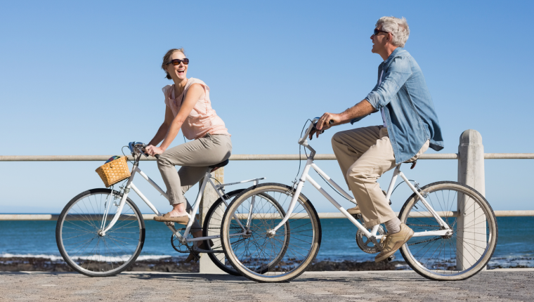 Couple takes bike ride by beach.