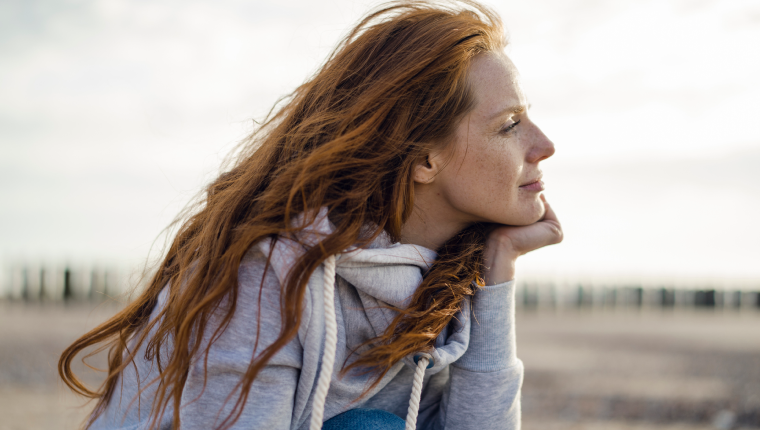 Woman on beach gazes out at water.