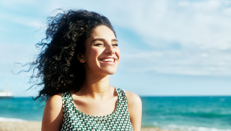 Woman enjoys a sunlit beach.